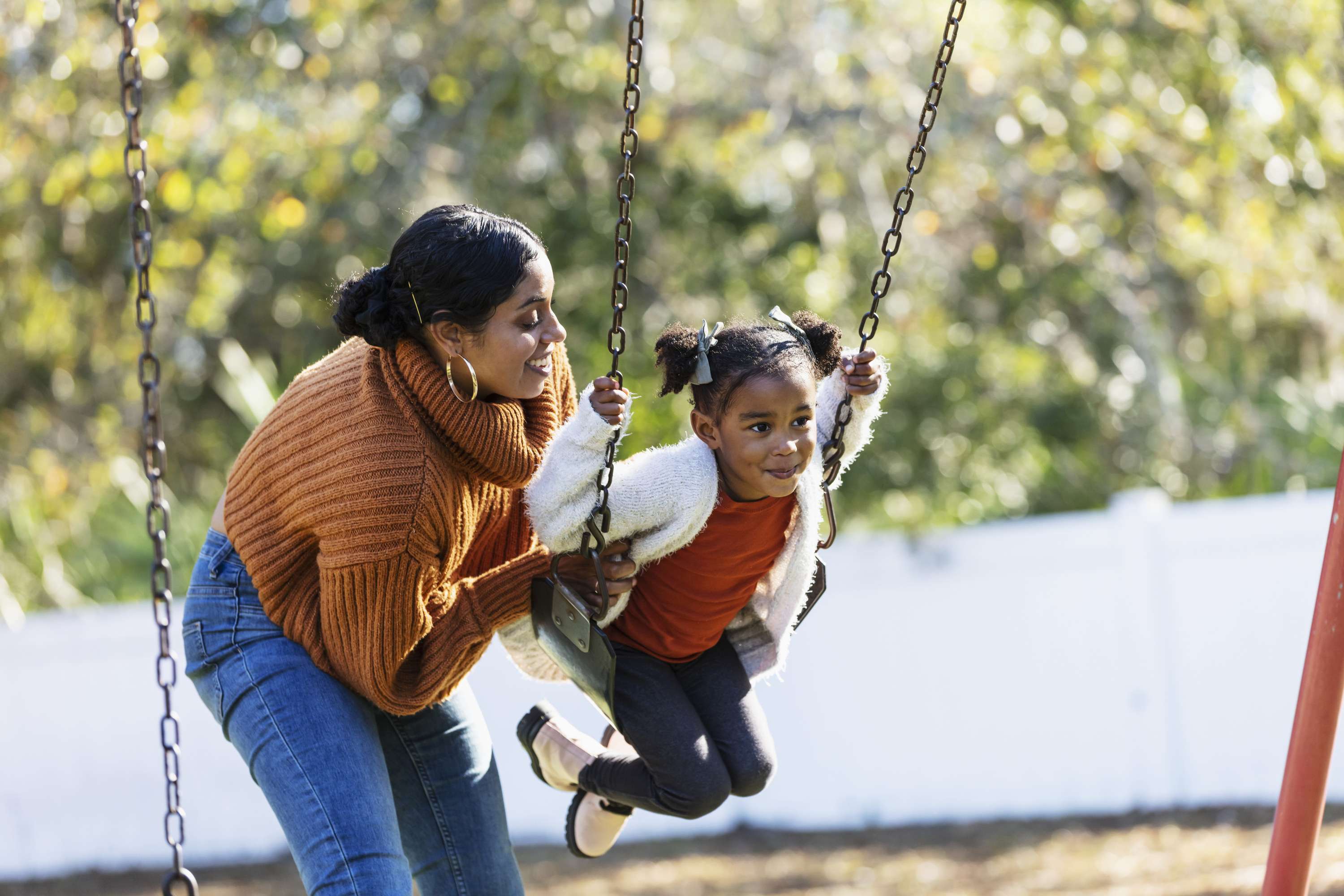 Woman pushing her daughter on the swings