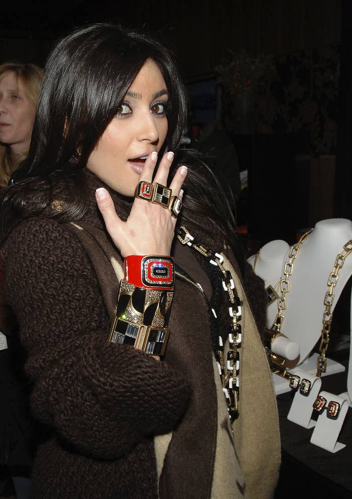 A much younger Kim posing for a picture while wearing several different bracelets, necklaces, and rings