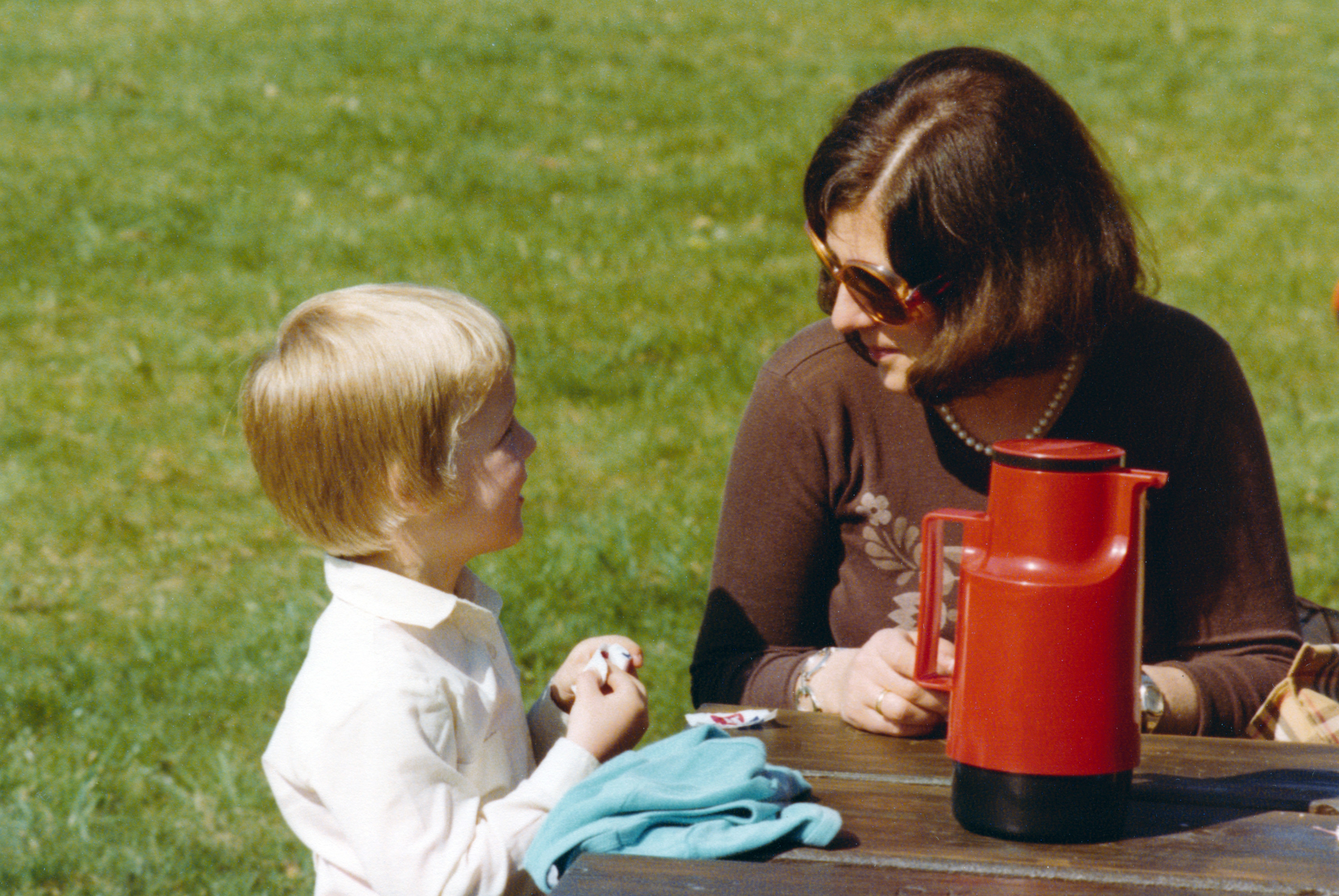 A woman sitting at a table with her child outside