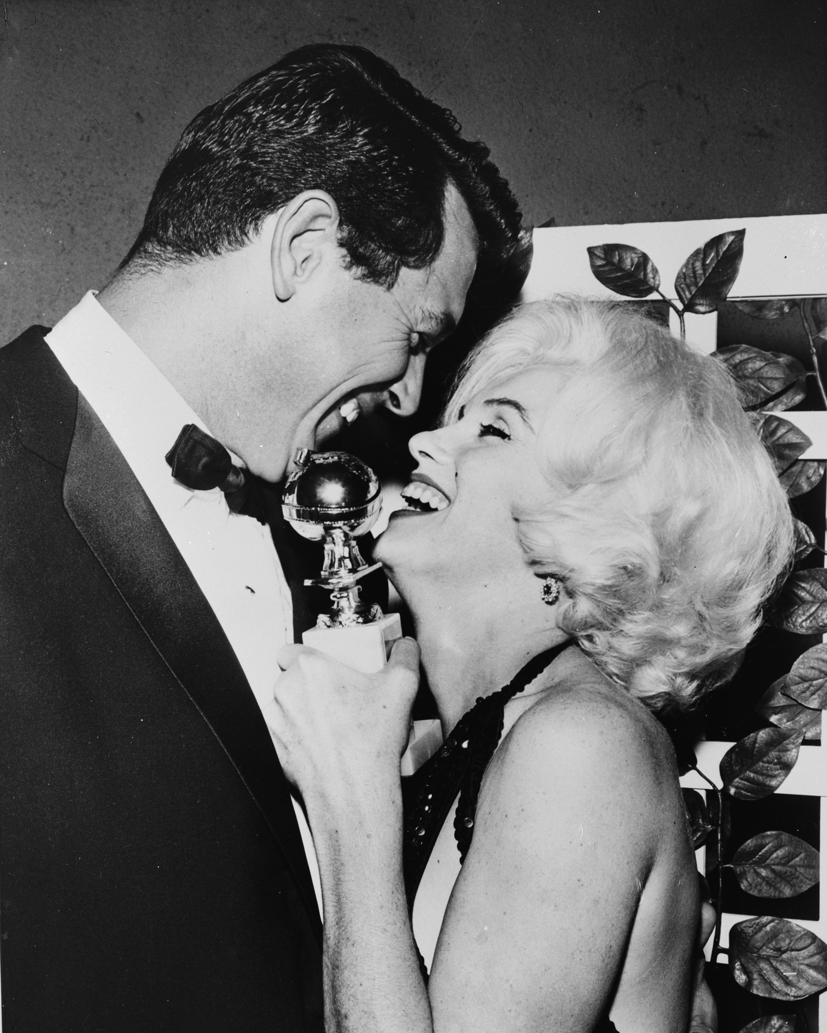 Marilyn laughing with a man while holding her Golden Globe