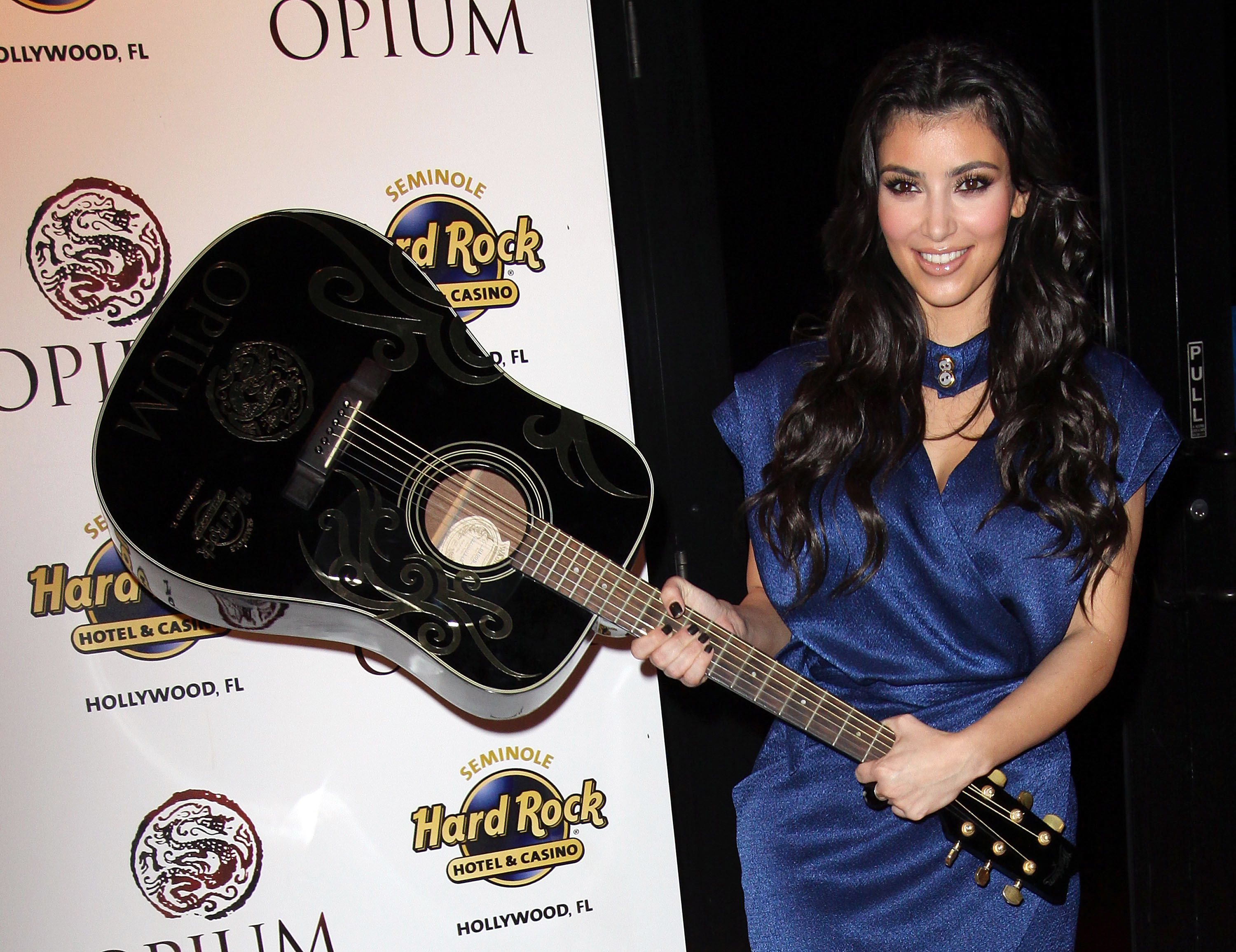 Kim holding a guitar by the head instead of the base