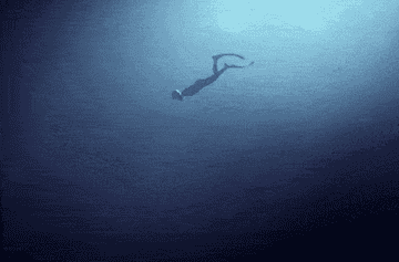 a scuba diver swimming deeper into the ocean