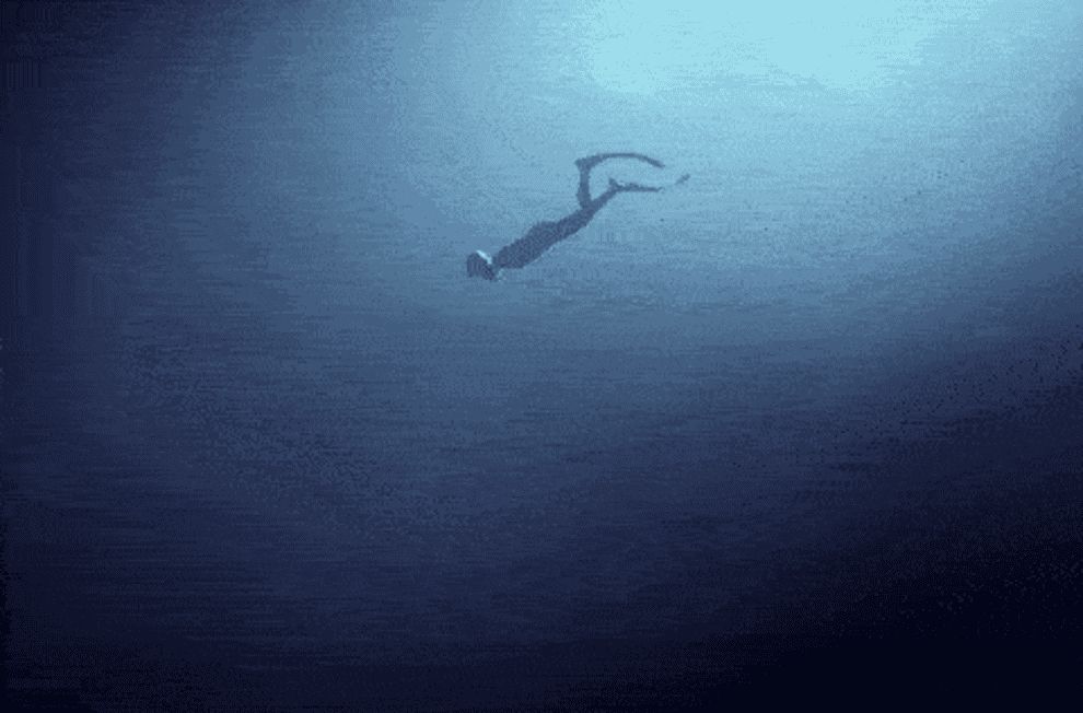 a scuba diver swimming deeper into the ocean