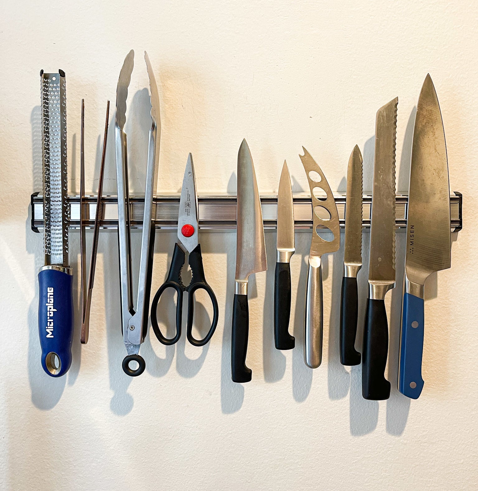 various cooking tools and knives hanging on a magnetic knife bar