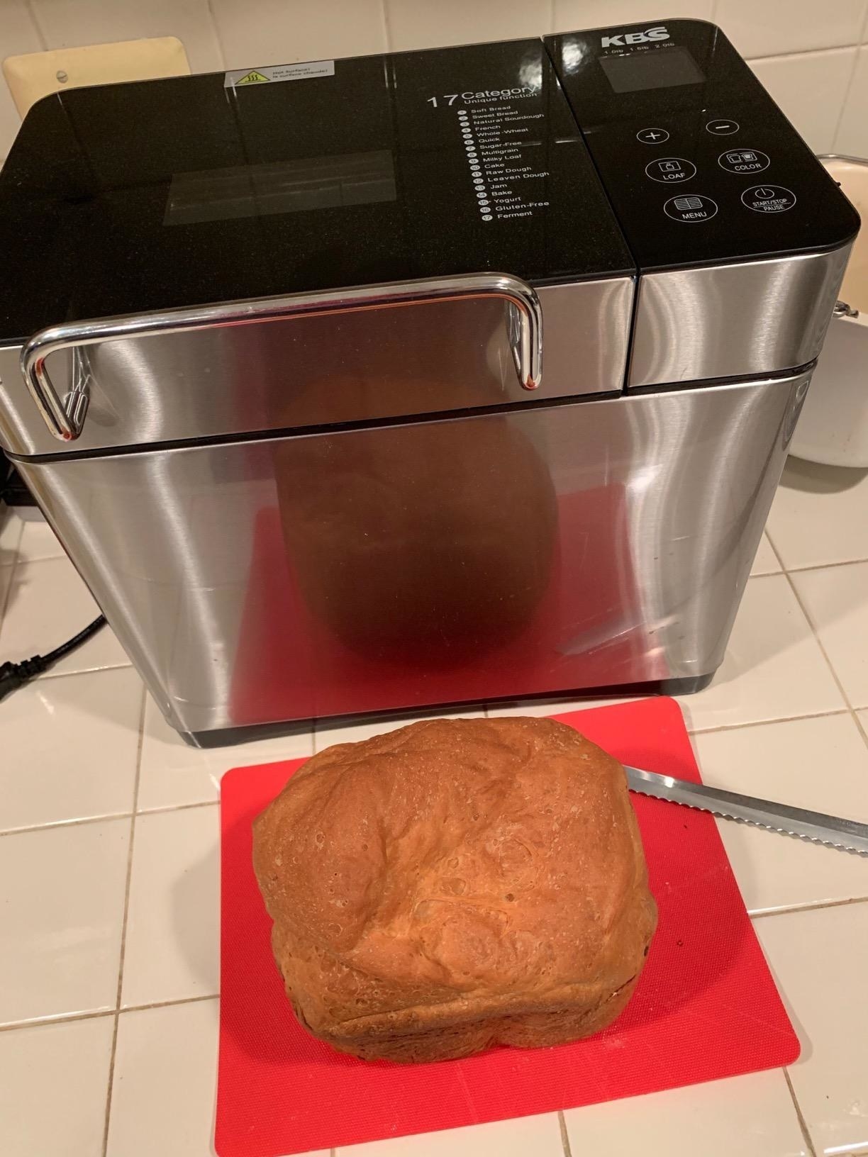reviewer's photo of the breadmaker with a loaf of bread sitting on cutting board