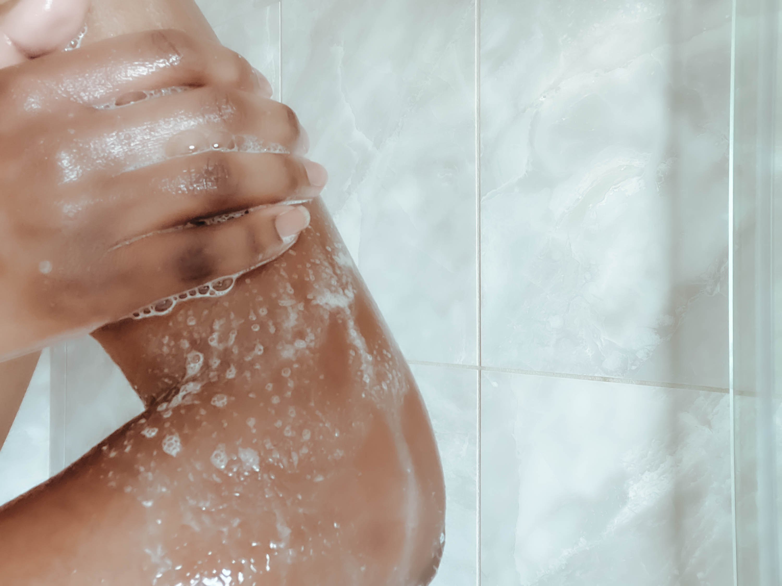 Close-up of person washing their upper body in the shower
