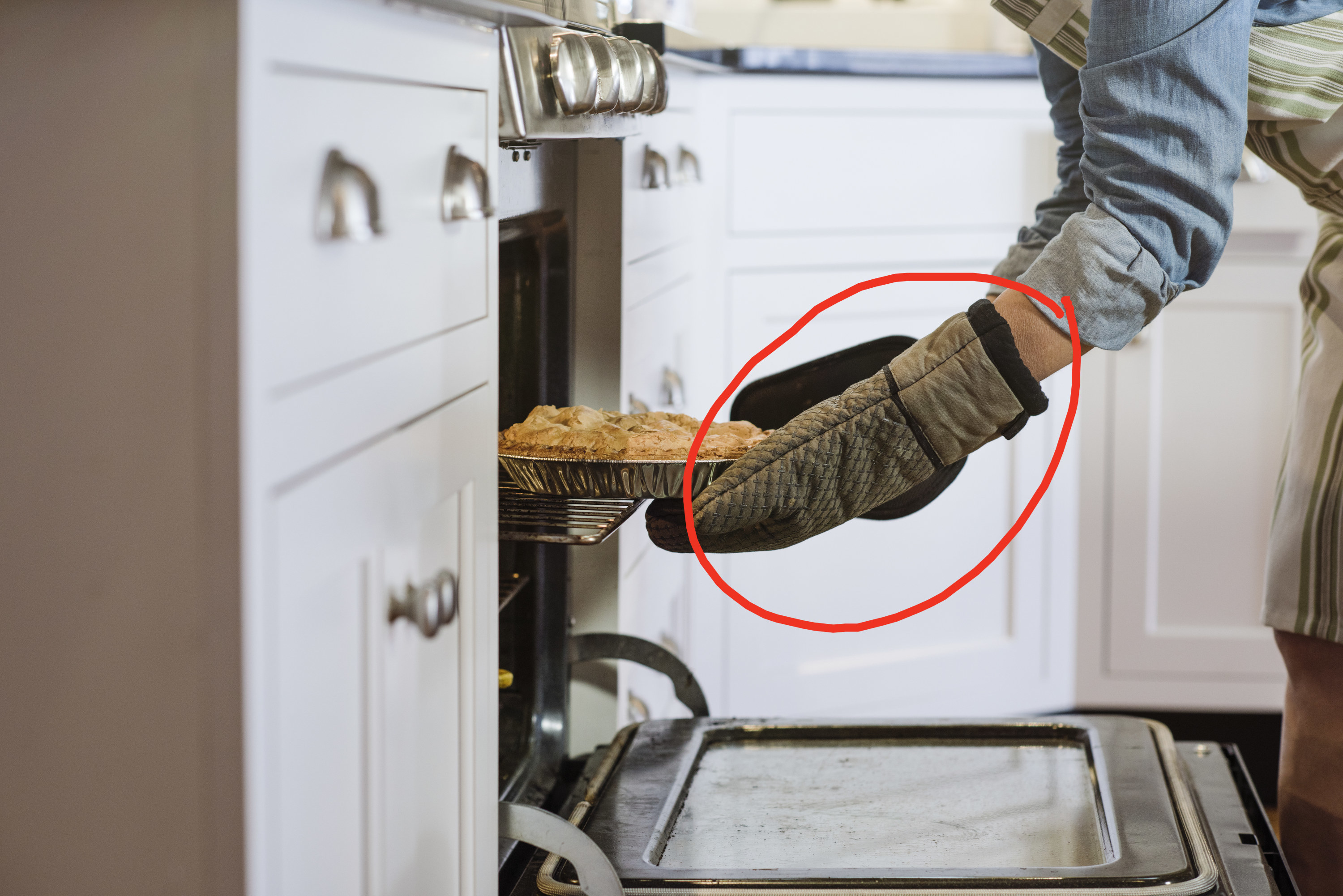 Person using pot-holders to remove a pie from the oven.