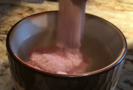 Pouring cocoa powder in a cup of water.