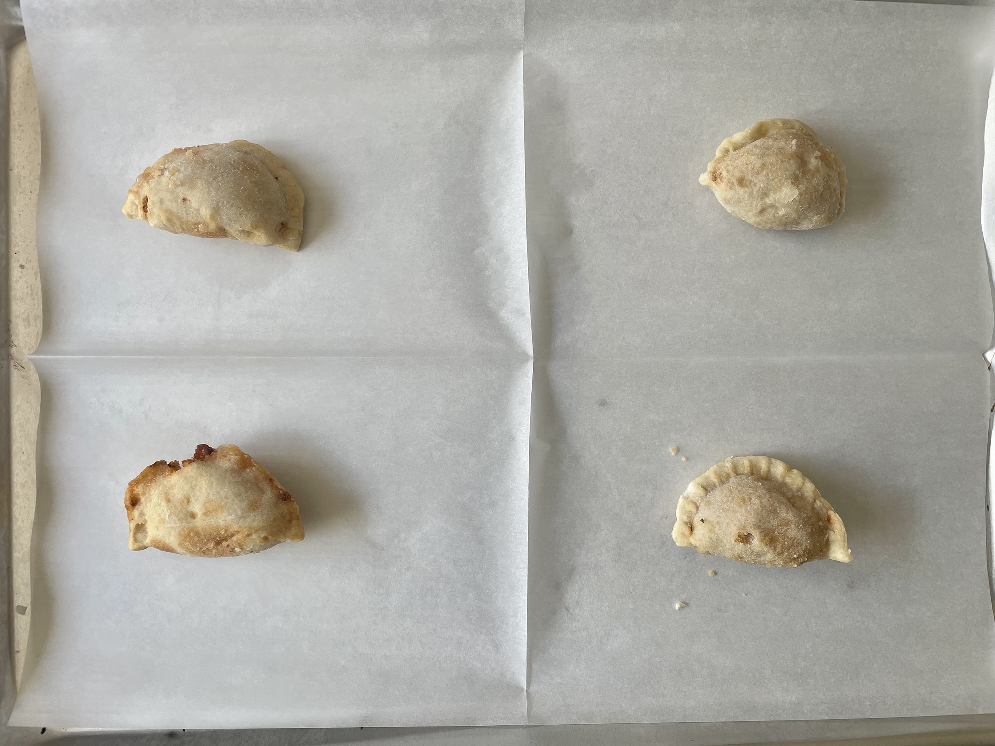 Uncooked empanadas on a baking sheet