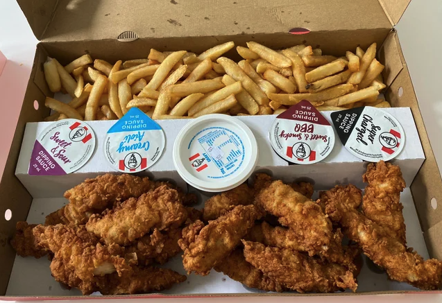 Chicken tenders and chips with a line of sauces down the middle