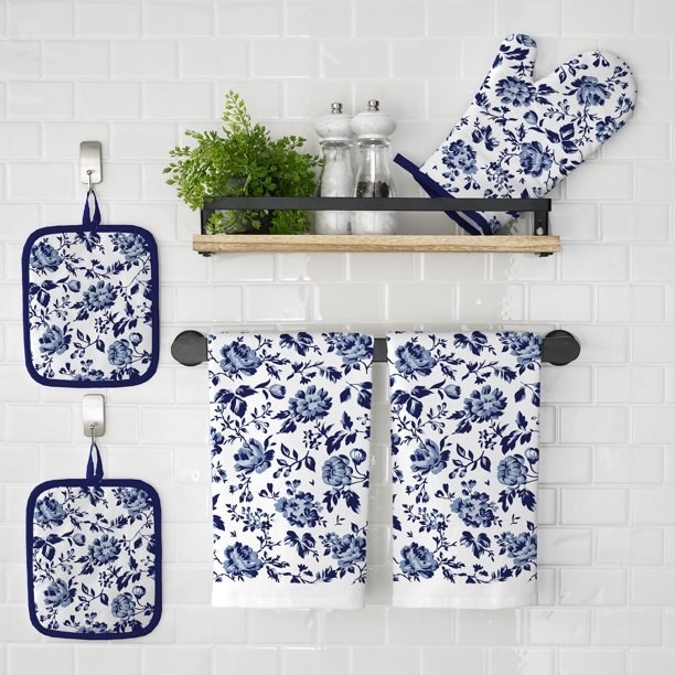 Blue and white floral kitchen set hanging on a white subway tile wall