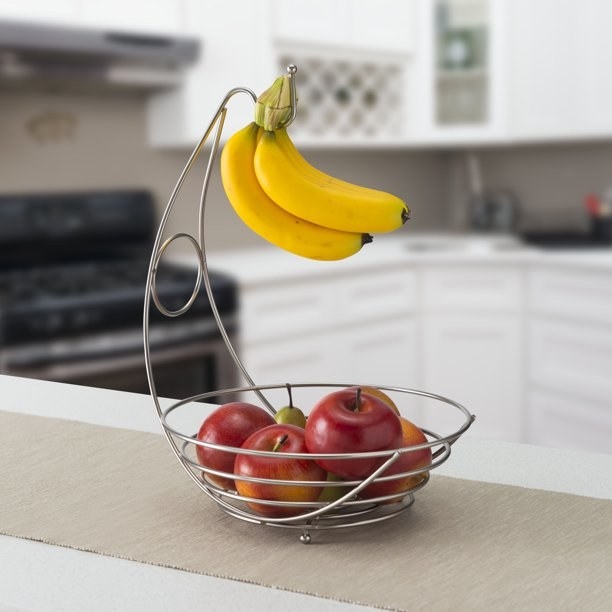 Fruit bowl with apples and bananas hanging on the banana tree