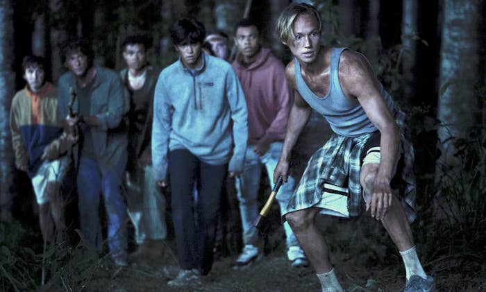 Still from The Wilds shows several boys edging towards something off camera in a forest