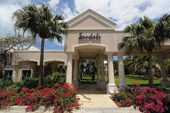 A building with the Sandals logo surrounded by trees and flowers