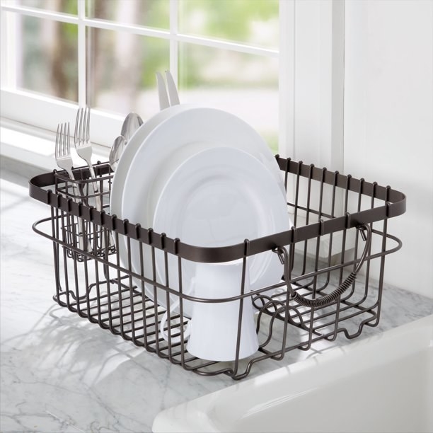 Dish drying rack filled with white dishes and silverware