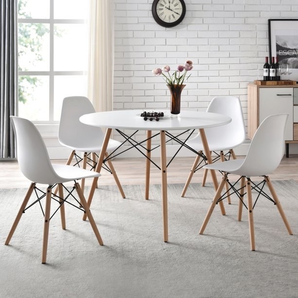 White dining table with wood legs and four matching chairs