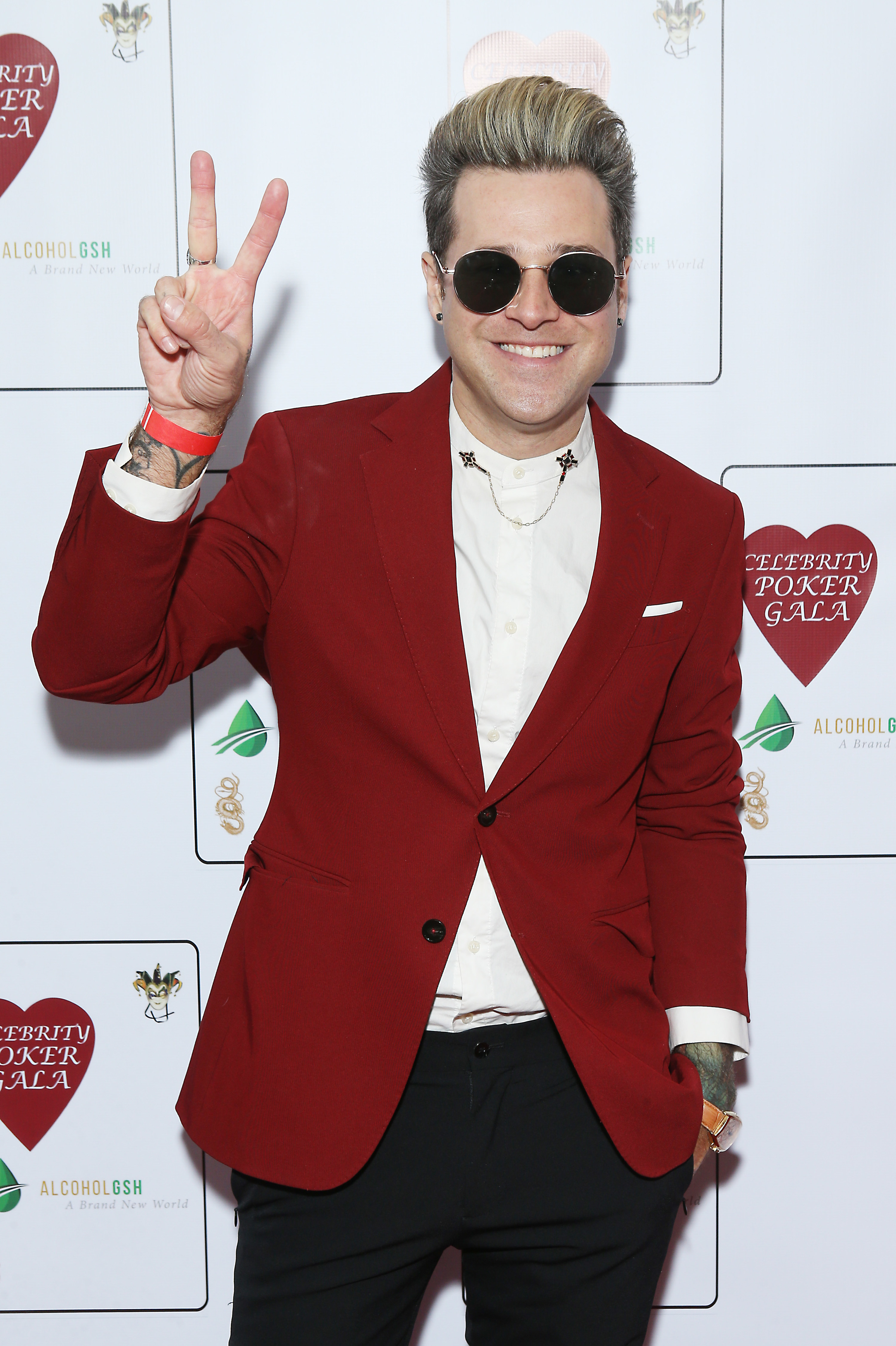 Ryan Cabrera wearing a red suit jacket and round sunglasses at the celebrity poker gala