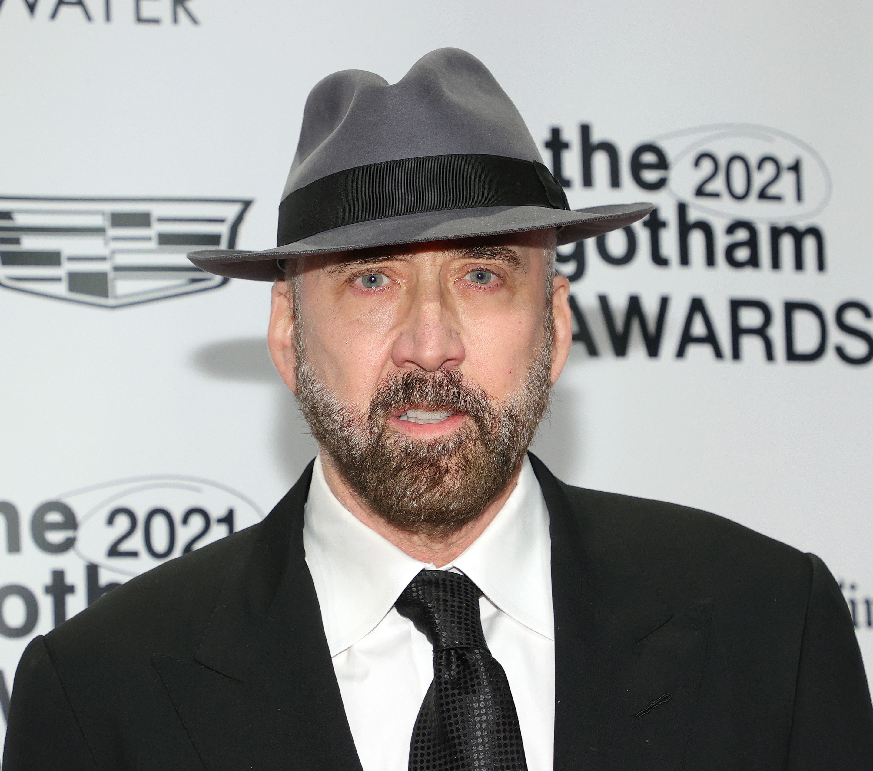 Nicolas Cage wearing a broad fedora and black-and-white suit on the red carpet for the Gotham Awards