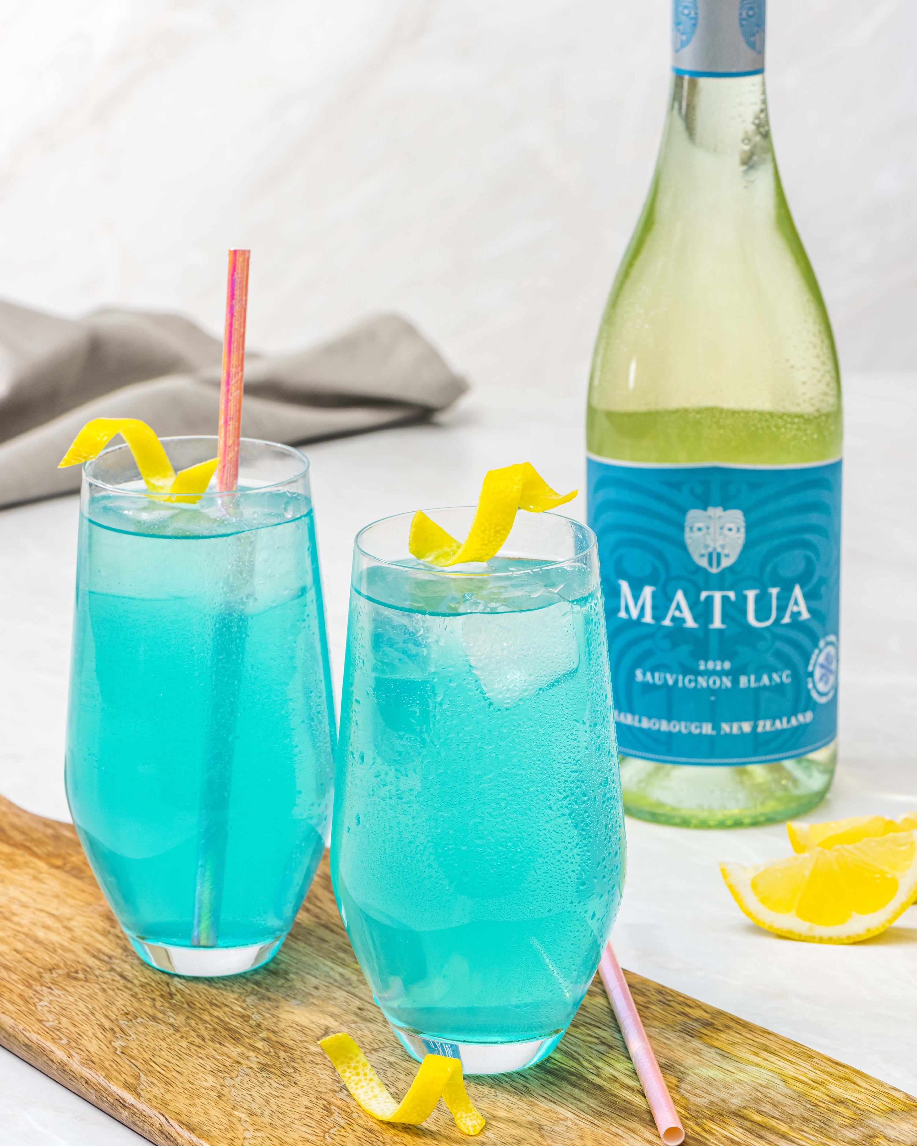 Two glasses of Blue Curacao Agua Fresca with fresh lemon and white wine.