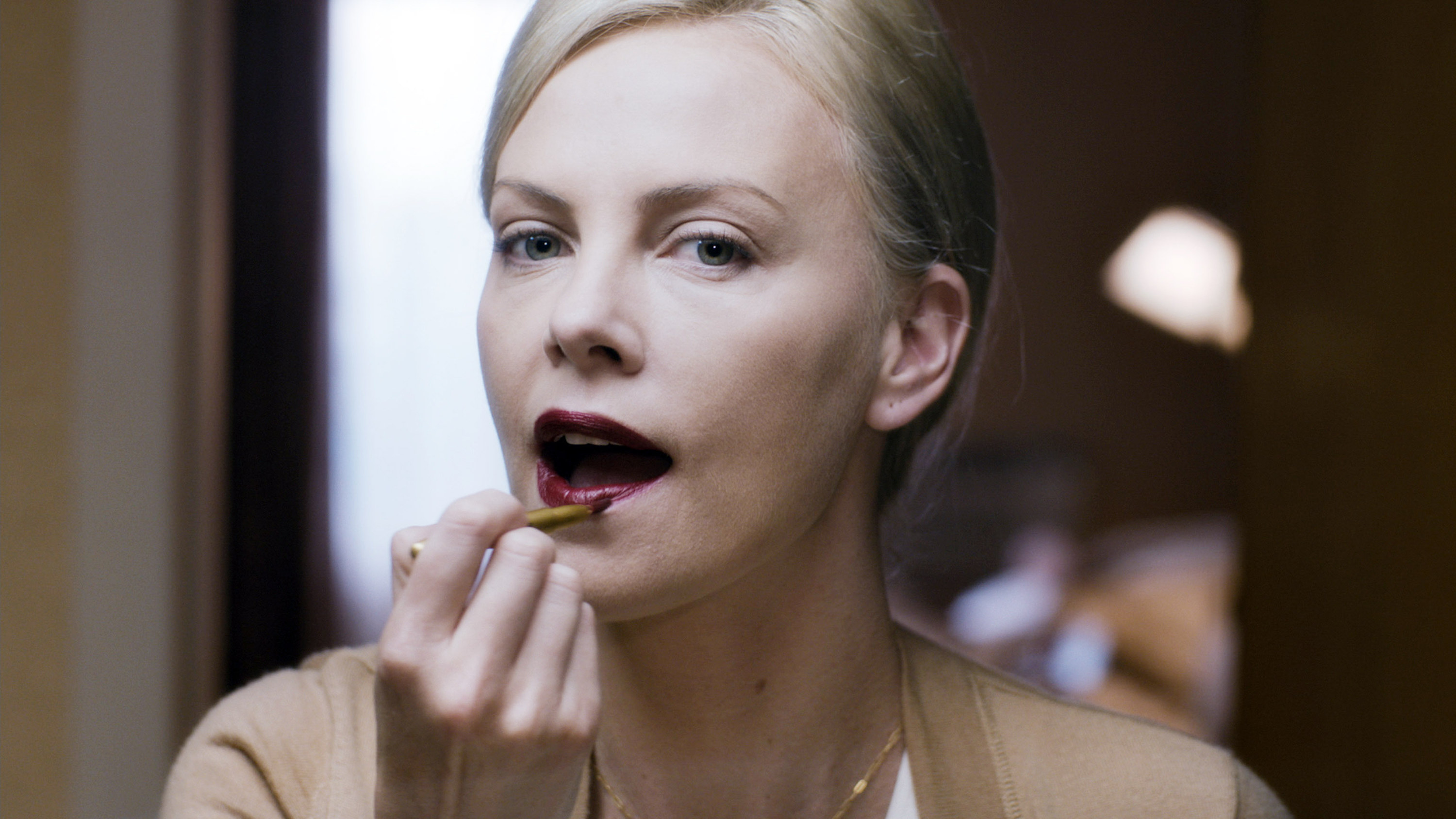 Charlize Theron applying dark lipstick