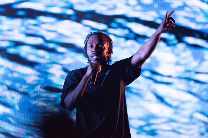Kendrick holding his hand up and performing with a microphone