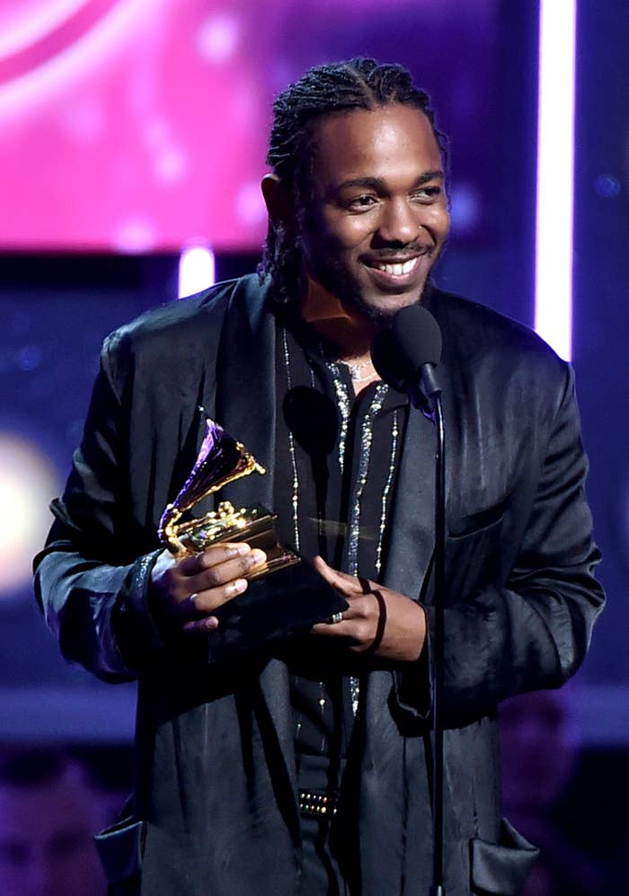 Kendrick smiling and holding an award at a microphone