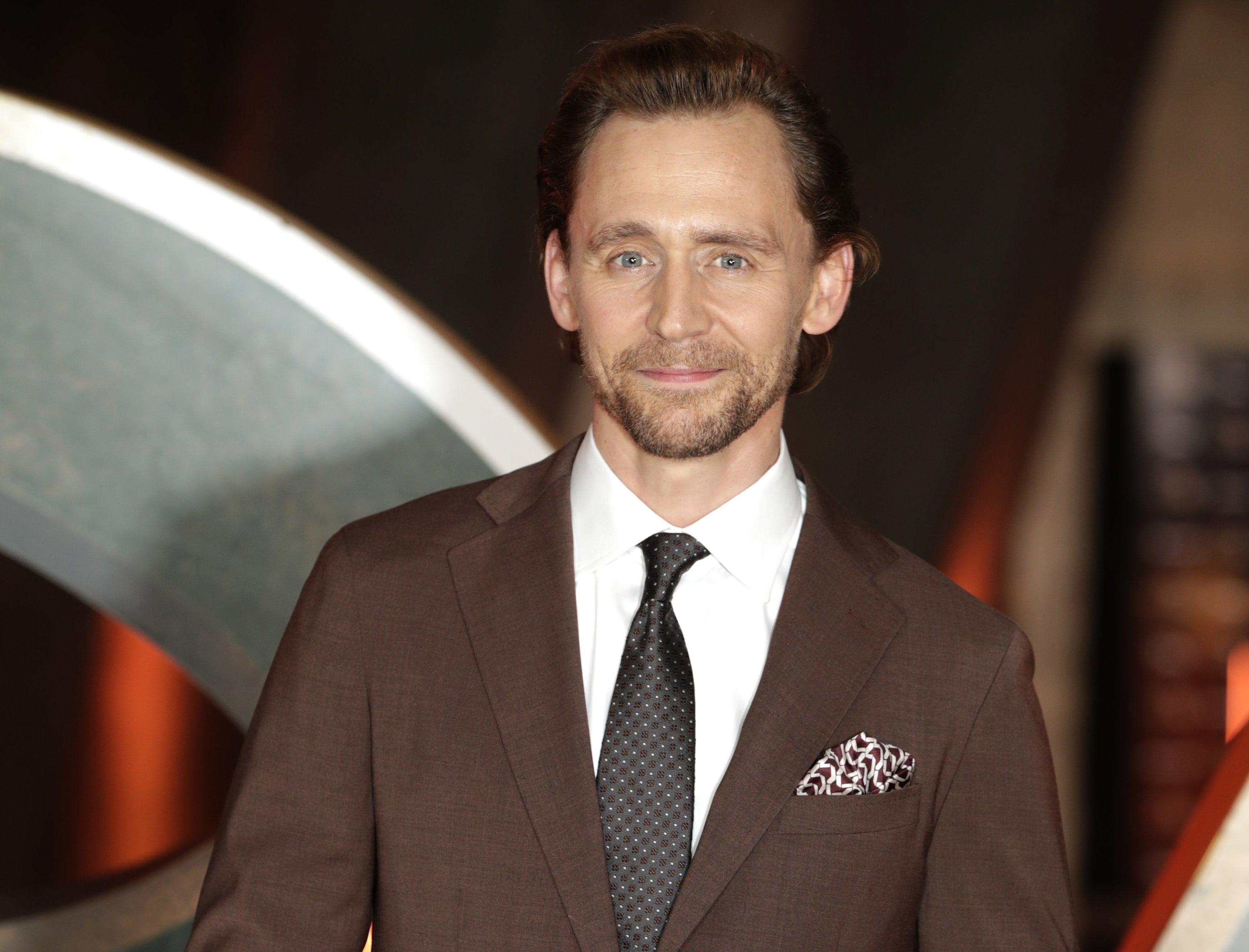 A close-up of Tom in a suit and smiling
