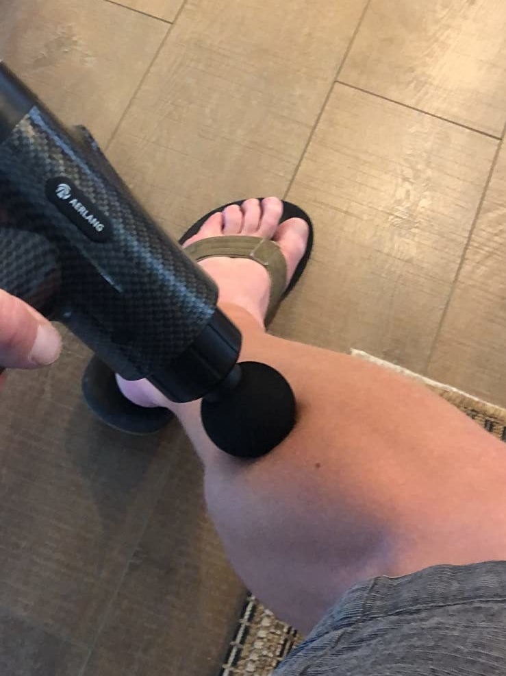 reviewer using the massage gun on their leg