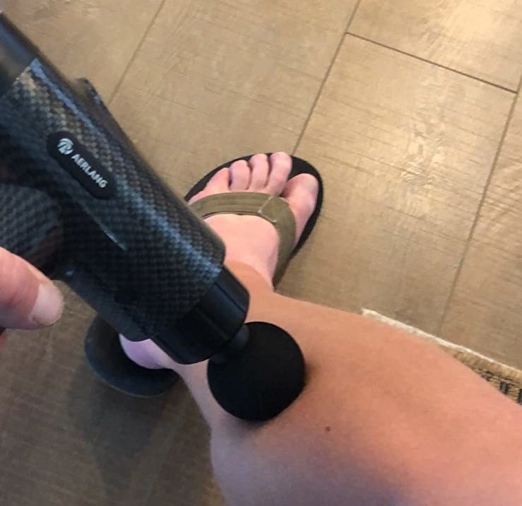 reviewer using the massage gun on their leg
