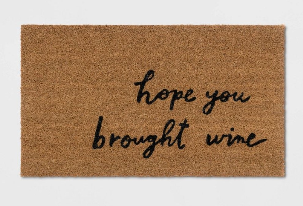 Brown doormat with black script writing on light gray background