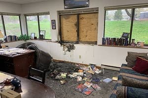 An interior of the office shows charred floors and walls, burned books, and a broken window covered up with wood