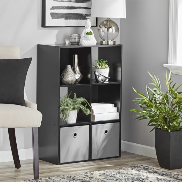 the cube organizer in black with plants and books in the shelves
