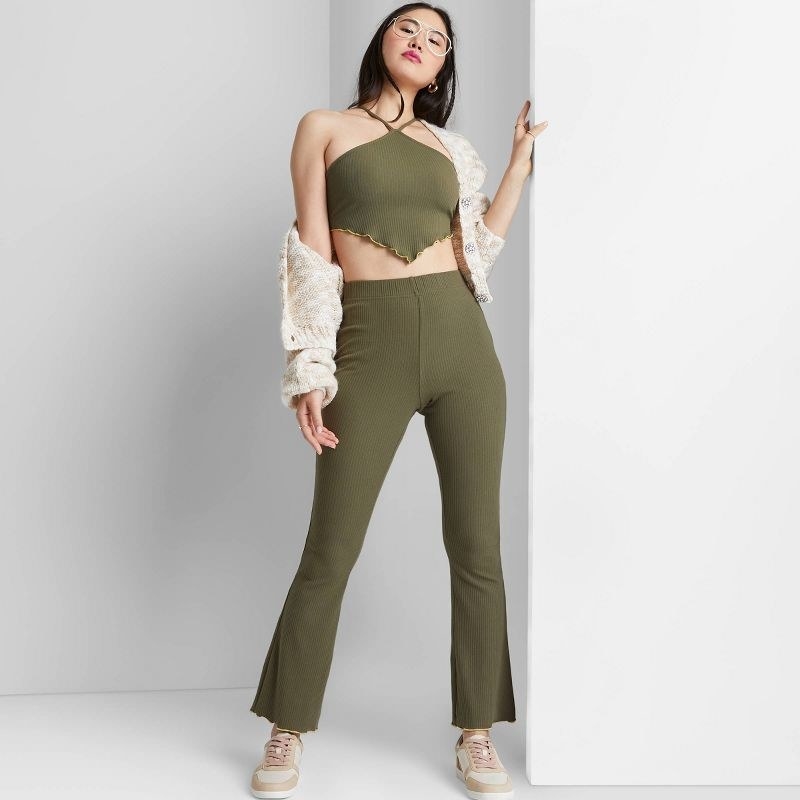 a model wearing green flare pants with matching halter top