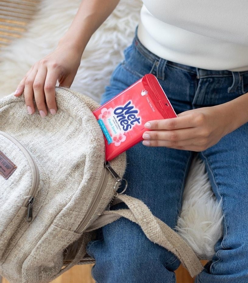 A person pulling a pack of wet wipes out of their backpack