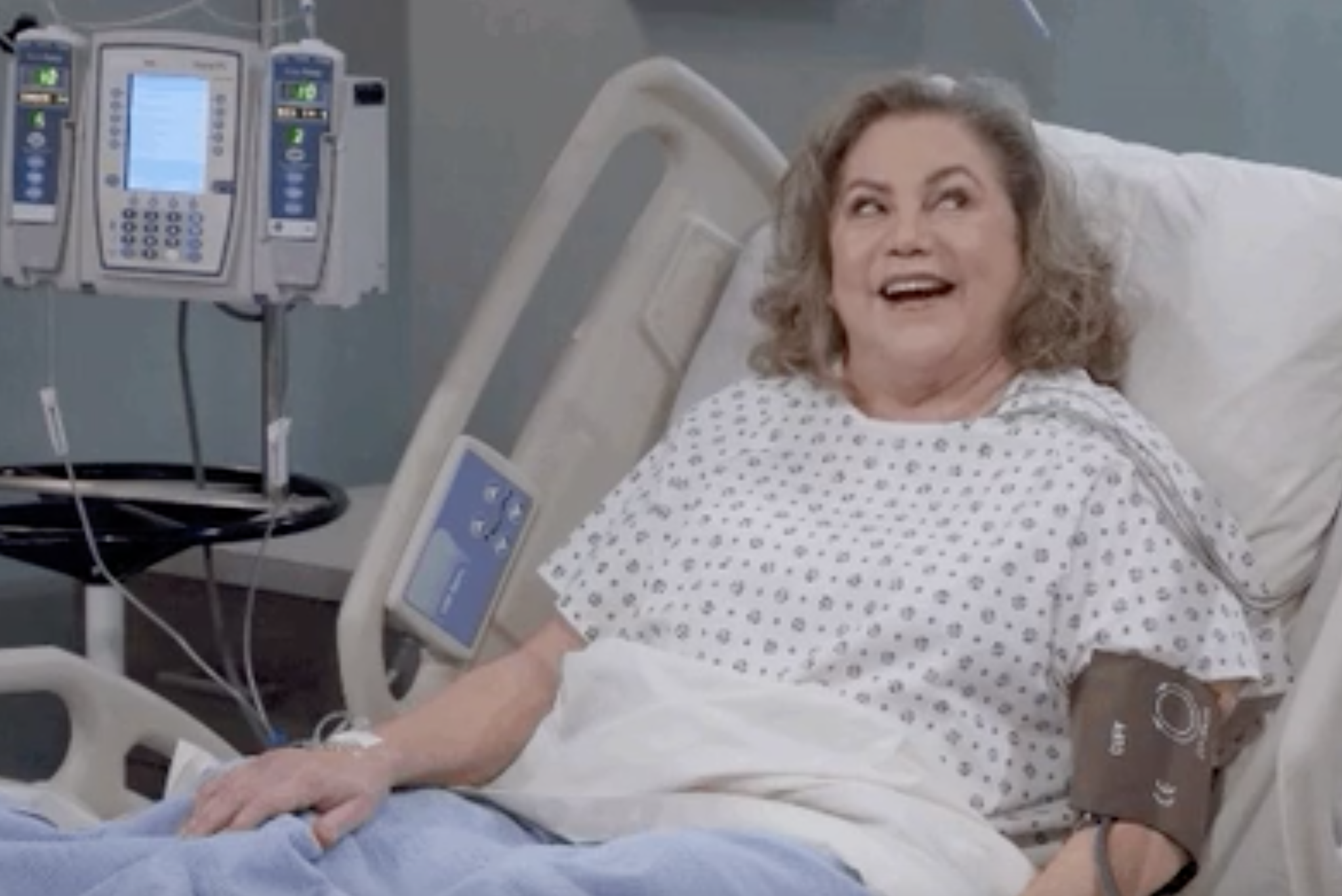 a woman smiling while sitting up in a hospital bed