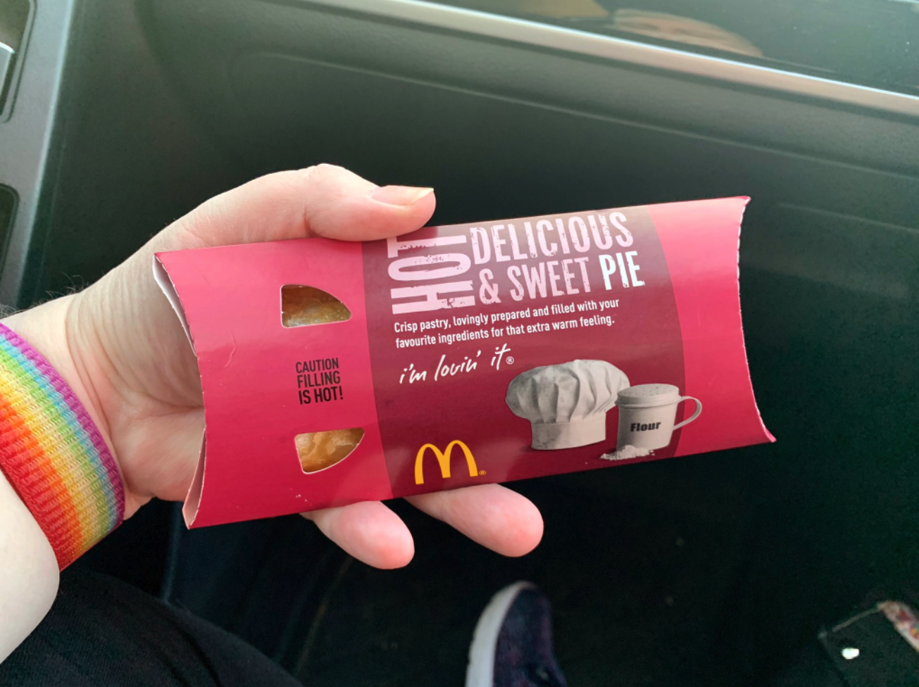 A hand holding a custard pie in a McDonald&#x27;s packaging box