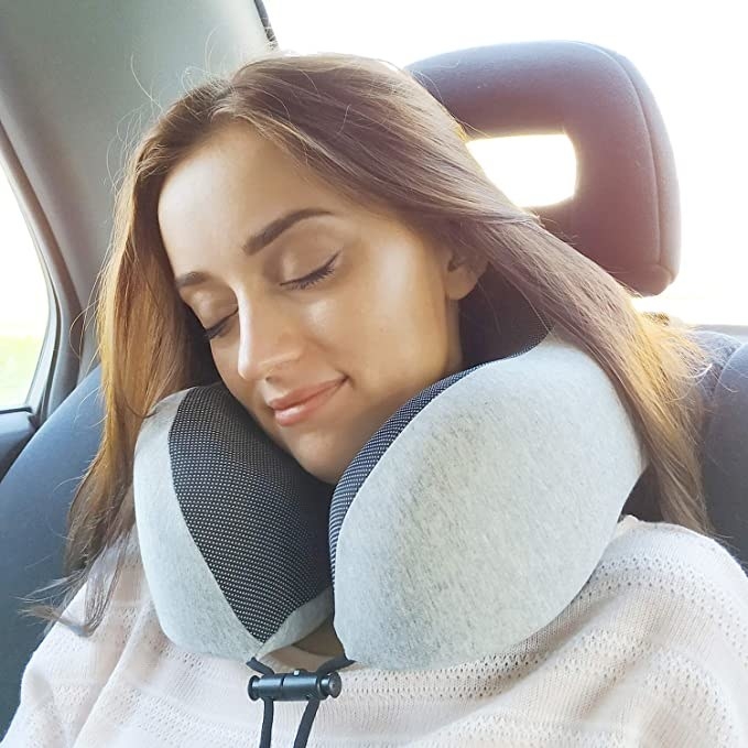 A person using the memory foam neck pillow in the car