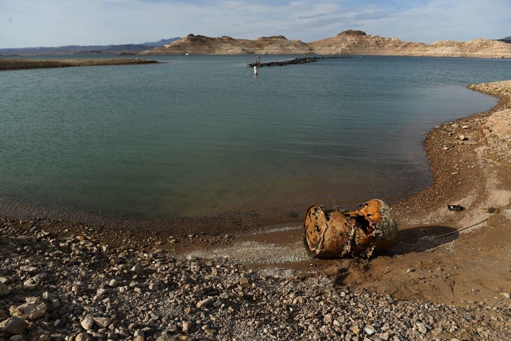 A broken, aged barrel on the side of a lake