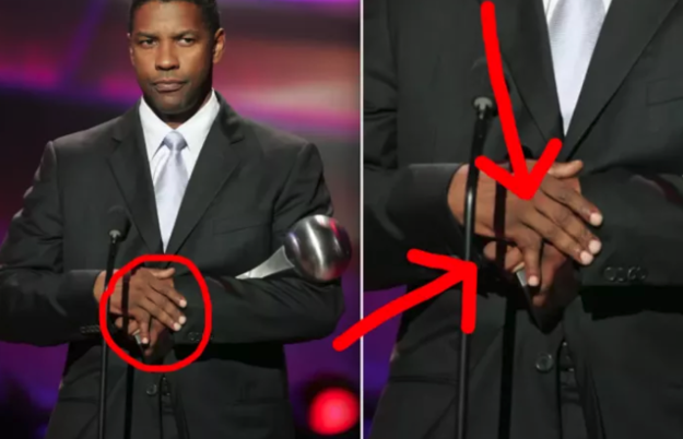 Denzel Washington standing on stage with his hands folded - his pinky finger is pointing at a strange angle