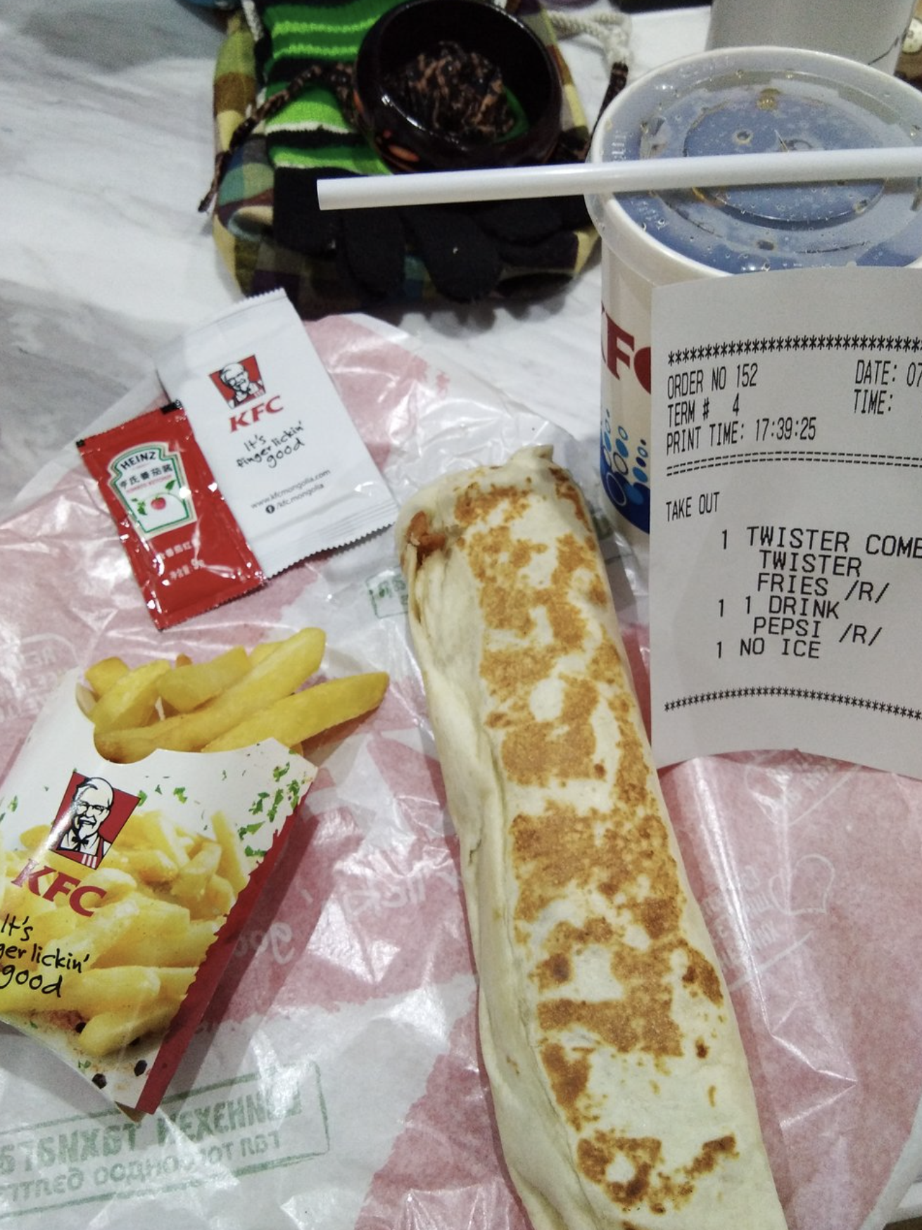 A KFC order featuring a toasted Twister, chips, a drink and sauce packets