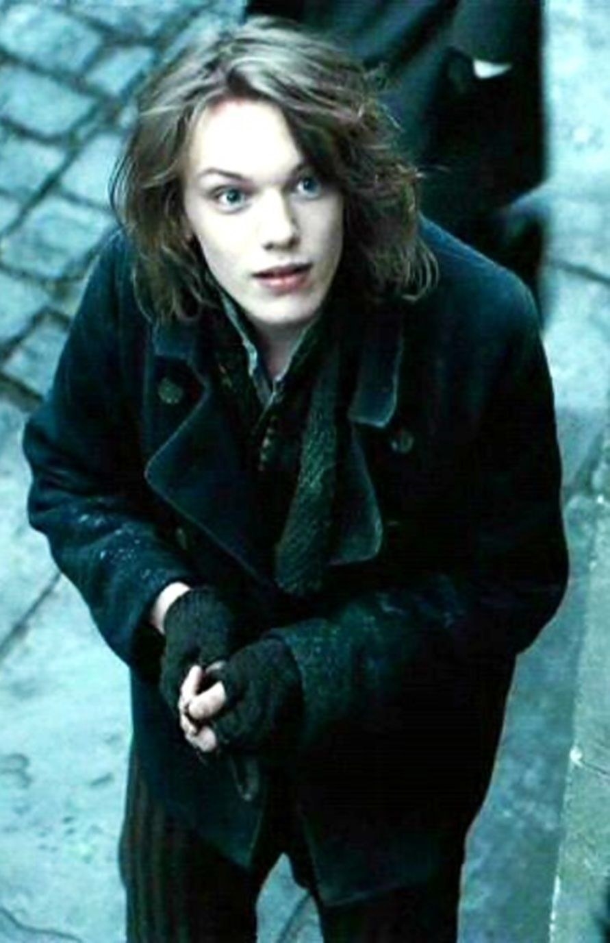 Jamie Campbell Bower standing in the street, looking up