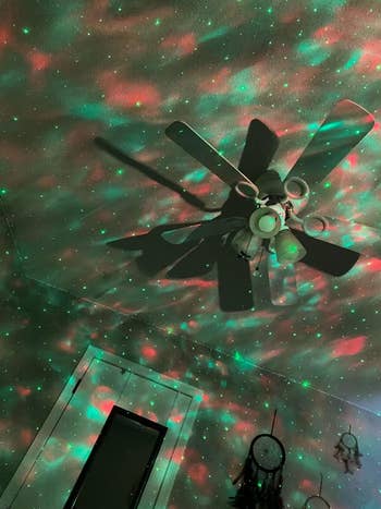 a green and reddish starry sky projected onto the ceiling