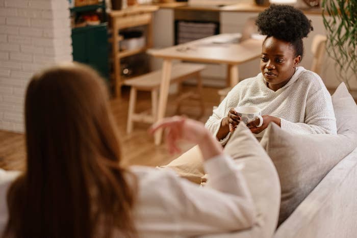 Two women sitting on a couch talking with one another
