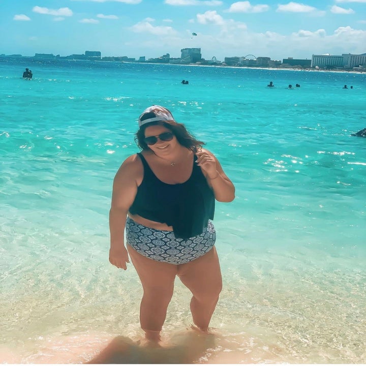 another reviewer standing in ocean wearing the black tankini top with medallion print bottoms