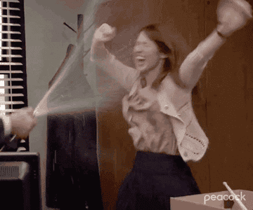 GIF of Ellie Kemper in The Office getting sprayed with champagne
