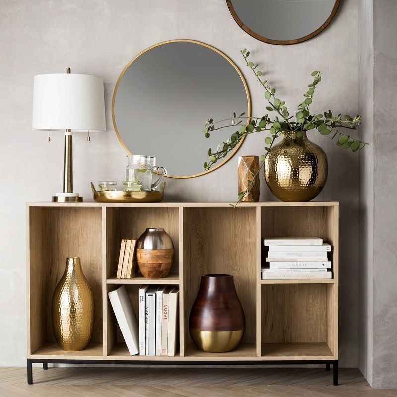 Bronze round mirror on wall above cubby cabinet