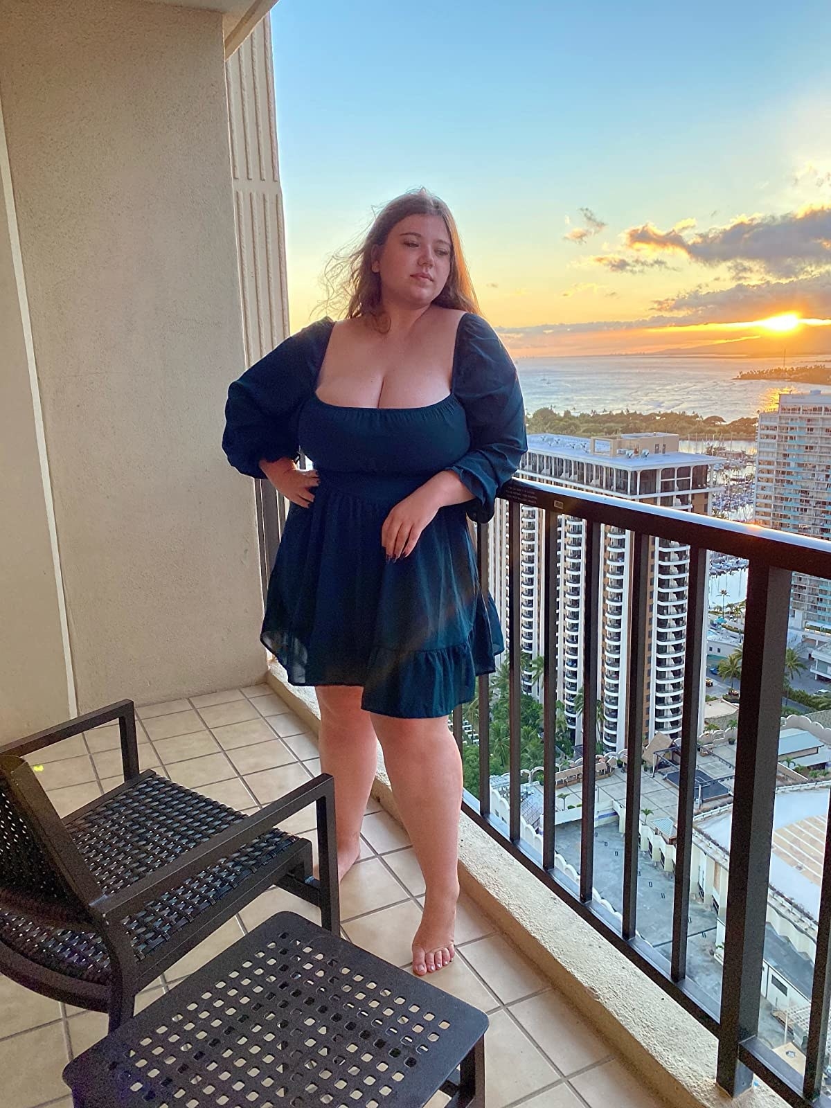 reviewer wearing the blue dress on a balcony