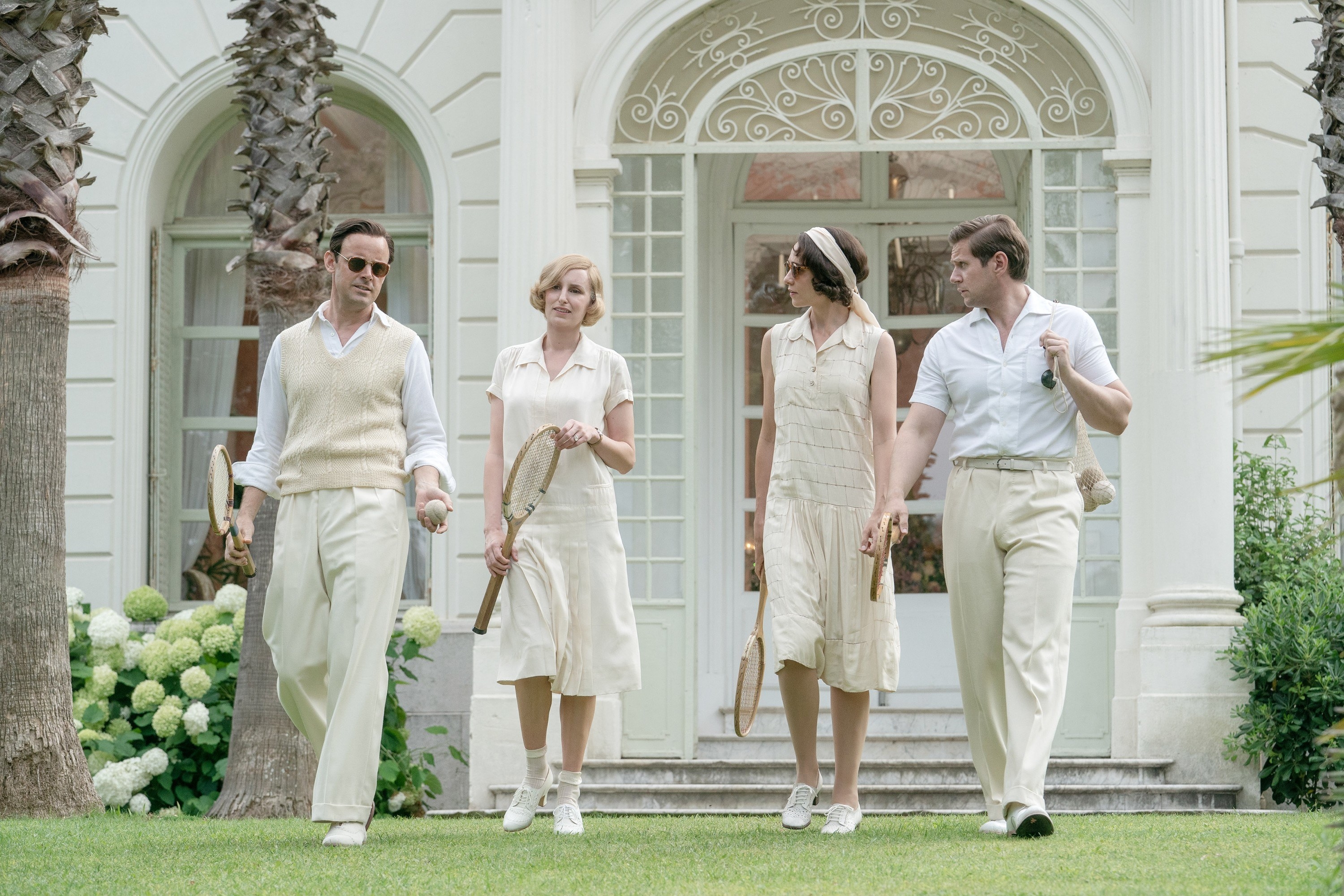 A group of men and women walking outside and holding tennis racquets and balls