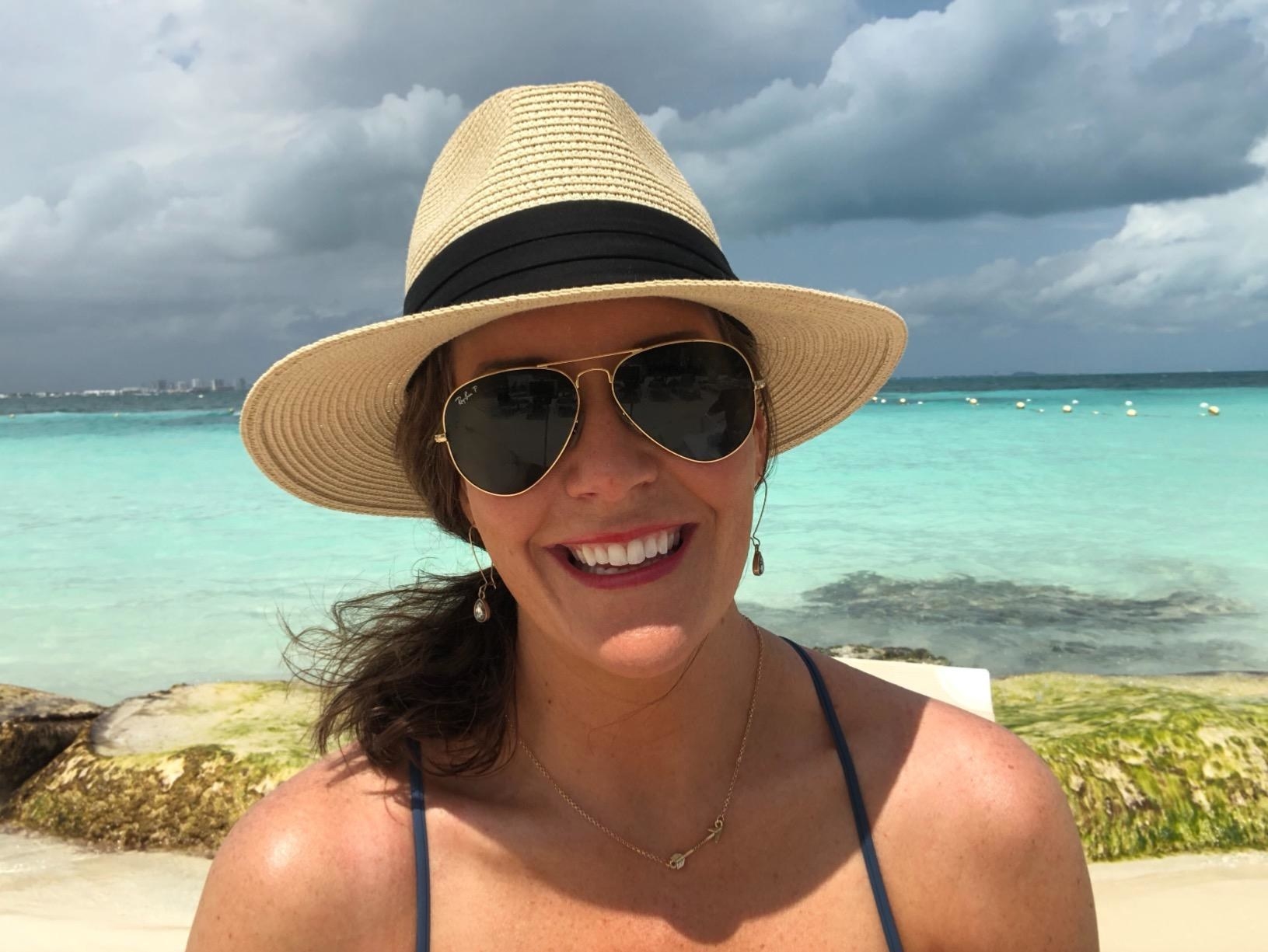 reviewer wearing the tan straw hat at the beach