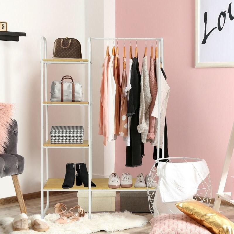 White garment rack with clothing hanging, side cubbies on left with shoes, box, and bags